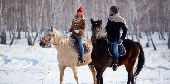 A couple horseback riding in a snowy forest