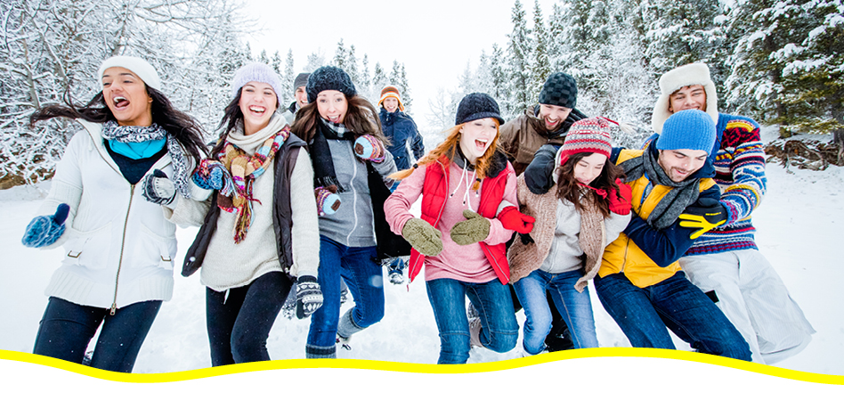 Group of young adults/friends running and laughing in the winter.