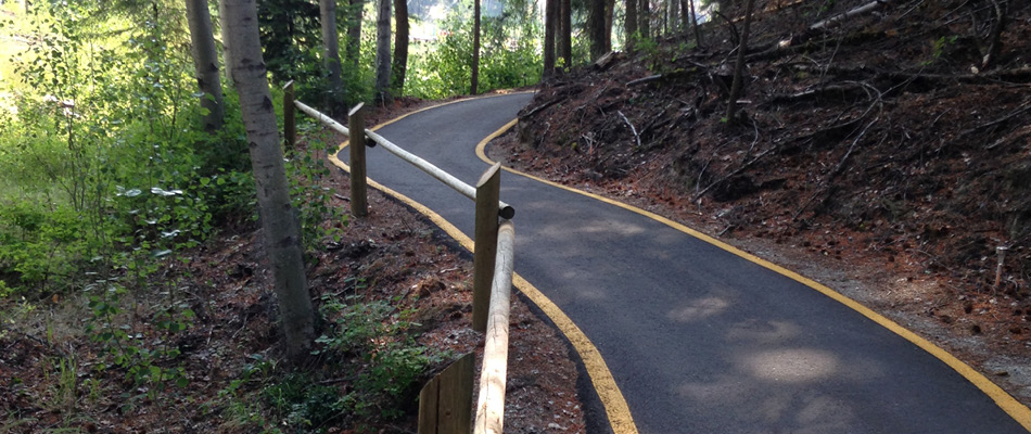A paved trail at Agur Lake Camp (BC) features accessible, paved trails with low grade changes and colour contrasting along the edge.