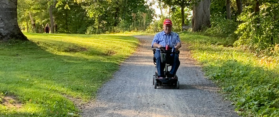 An adult on a mobility scooter on a wide, hard-packed gravel surface
