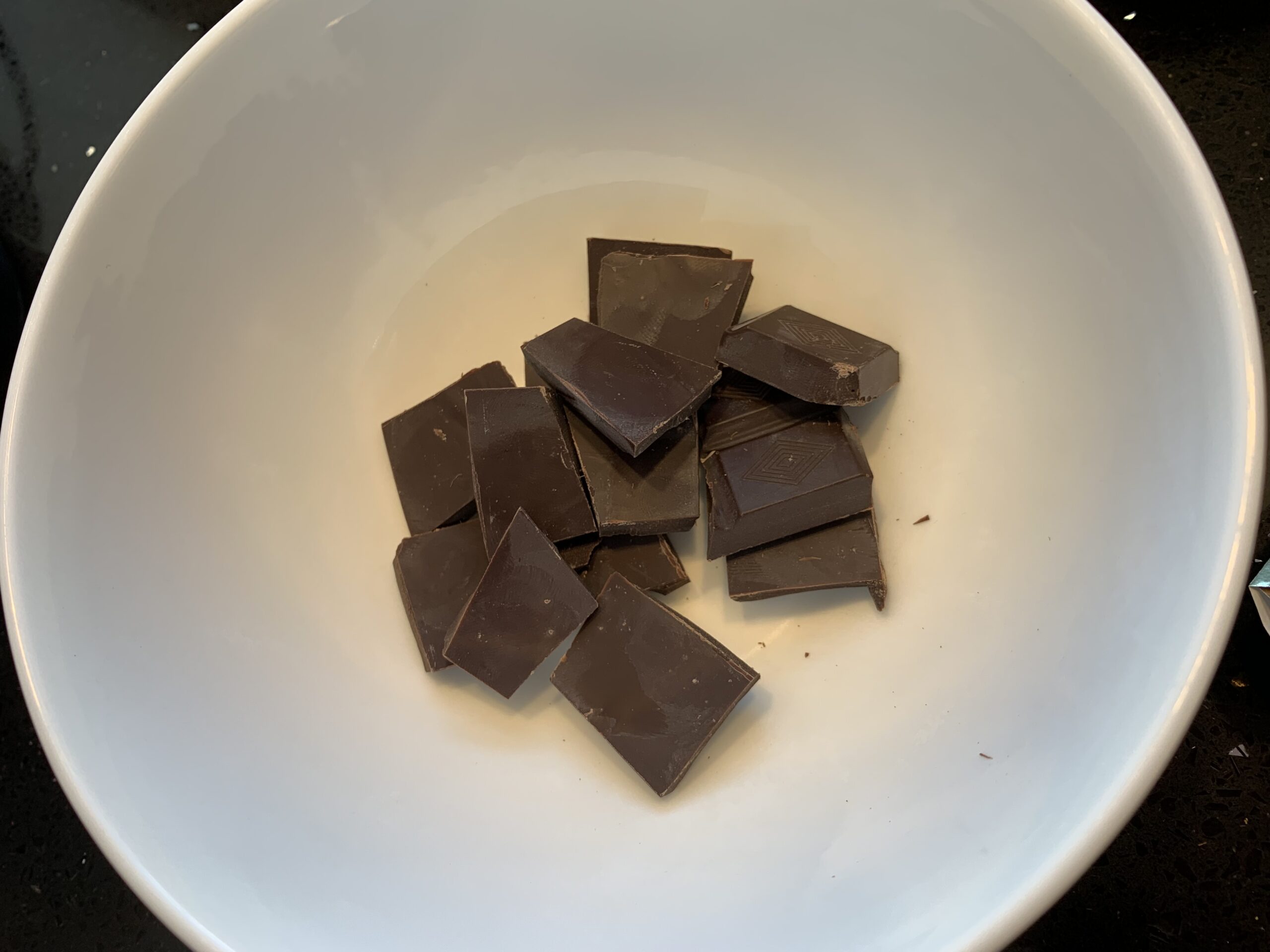 Image of medium white bowl with square of dark chocolate in int