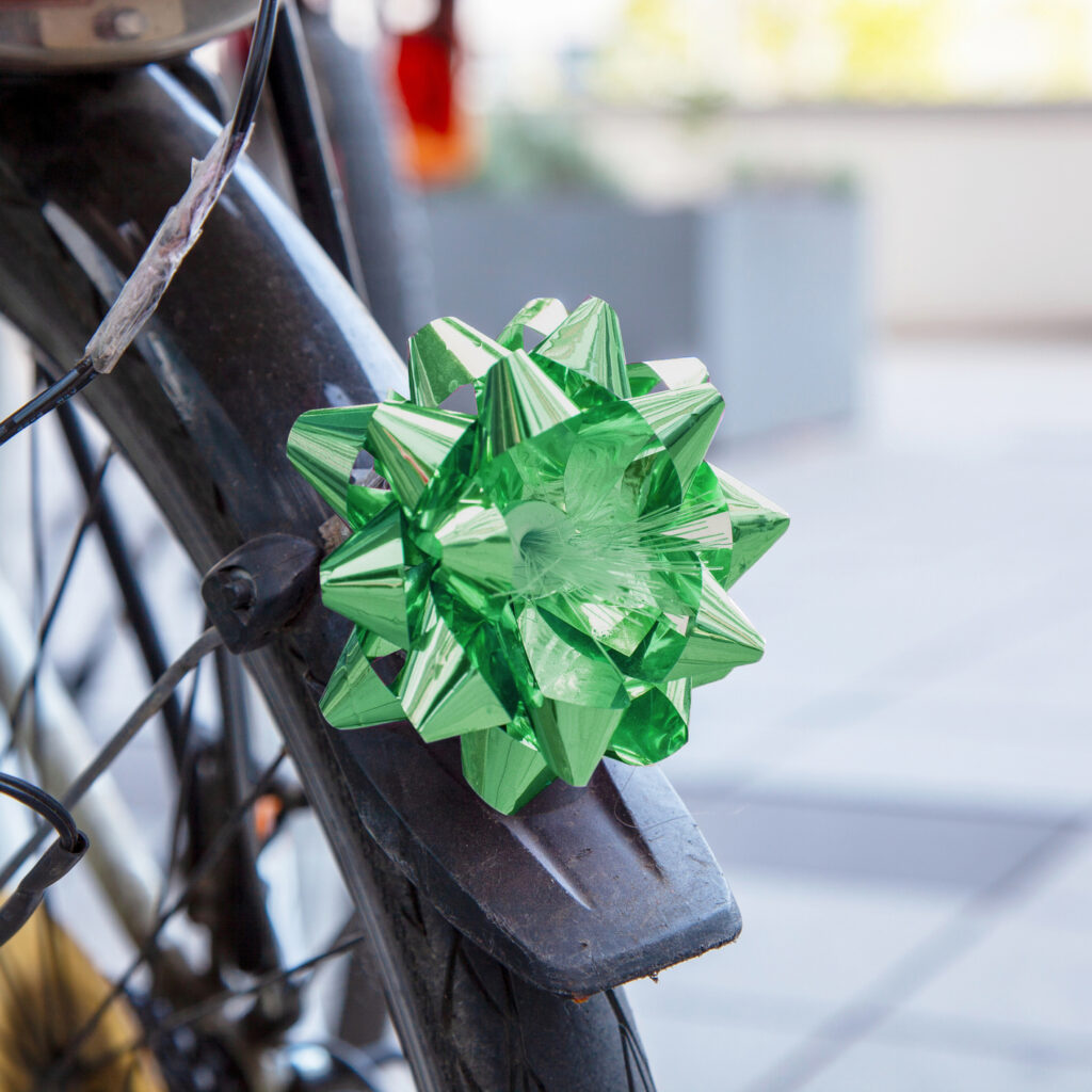 A wheel on a bike with a green ribbon, biking is an example of eco-friendly activities