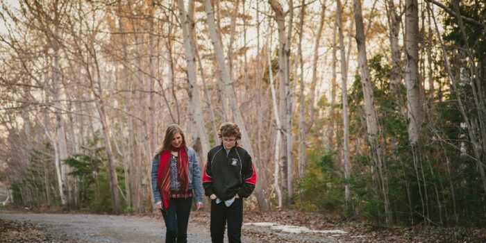 Leave No Trace Principles: To young adults walking along a gravel path, surrounded by trees.