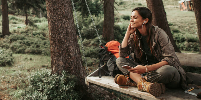 A female adult sitting on a bench with headphones in listening to music