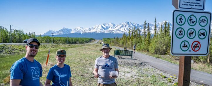 Trail Care Grant volunteers standing by a Trans Canada Trail sign at the side of a trail