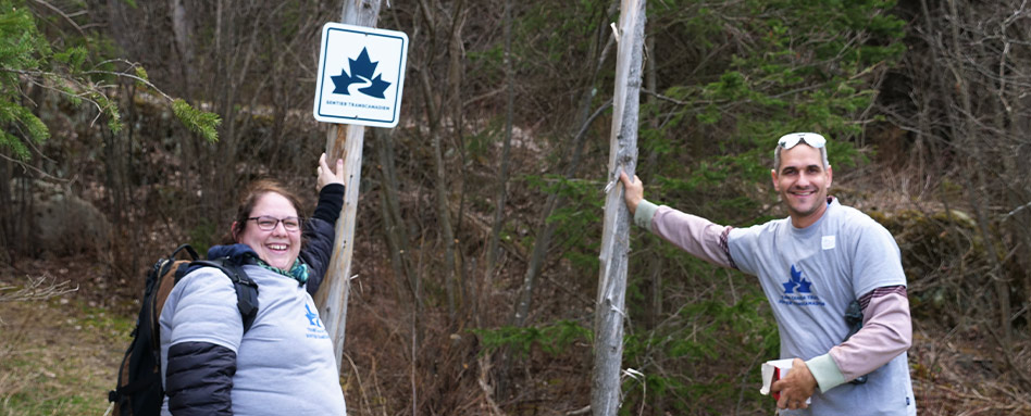 Trail volunteers standing in front of a Trans Canada Trail sign