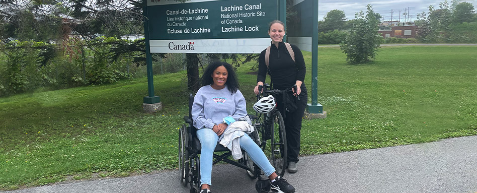 A cyclist next to a wheelchair user on a section of accessible trail.
