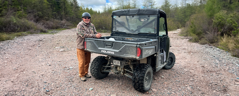 A man standing beside an ATV on a Rail Line Badger to Howley Newfoundland