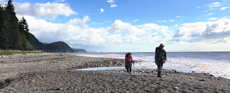 Two adults walking along the coastline at Fundy Trail