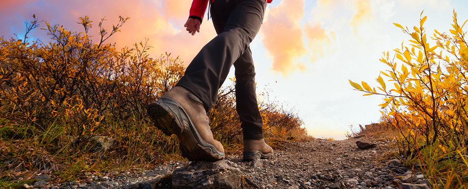 close up of someone wearing boots walking uphill on gravel