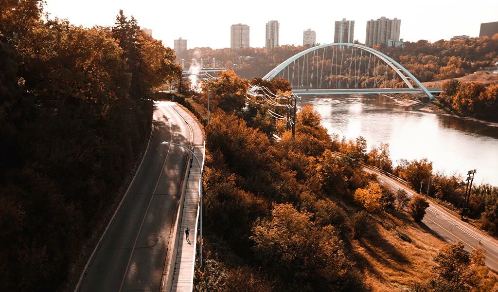 The cover photo of Trans Canada Trail's imapct report. It shows a person running a boardwalk along the North Saskatchewan River in Edmonton, Alberta