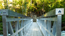 A wooden bridge over water with a Trans Canada Trail sticker on the post