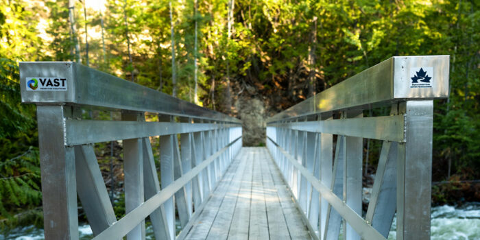 A wooden bridge over water with a Trans Canada Trail sticker on the post