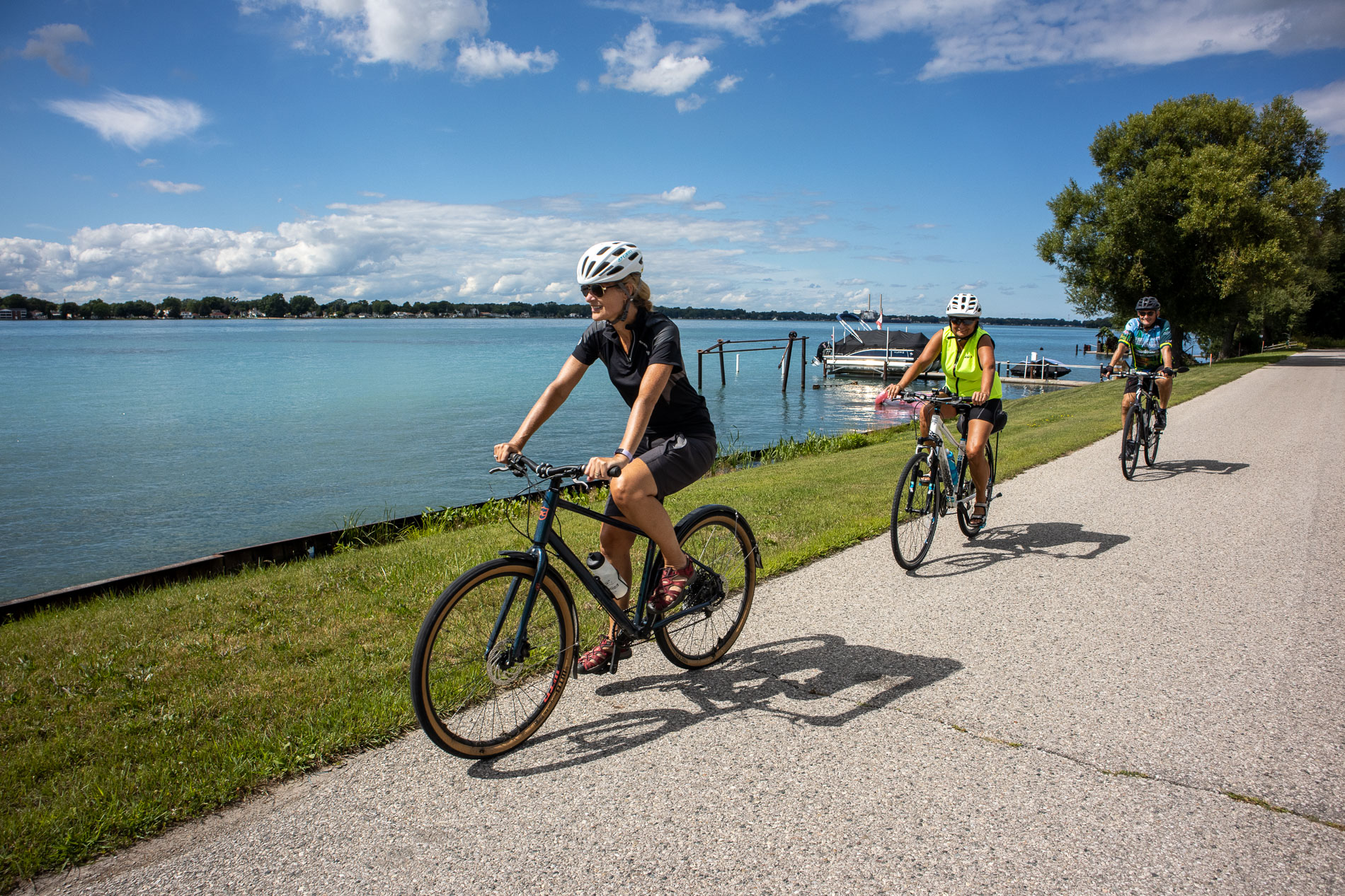 Three people riding their bikes along a waterfront trail in Windsor