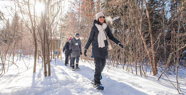 A group of adults enjoying a snowy walk on snowshoes down a wintry path