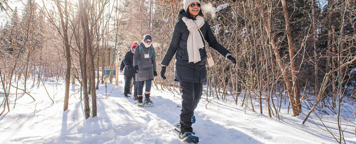 A group of adults enjoying a snowy walk on snowshoes down a wintry path