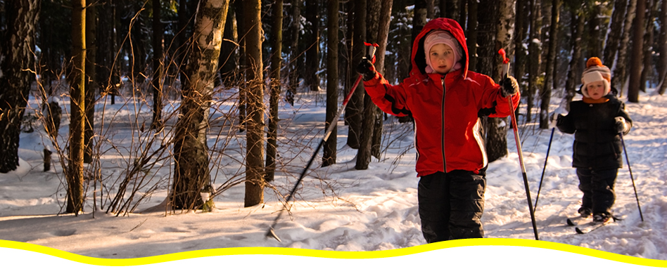 Two children cross-country skiing on a trail in the winter. Deux enfants font du ski de fond sur une piste en hiver.