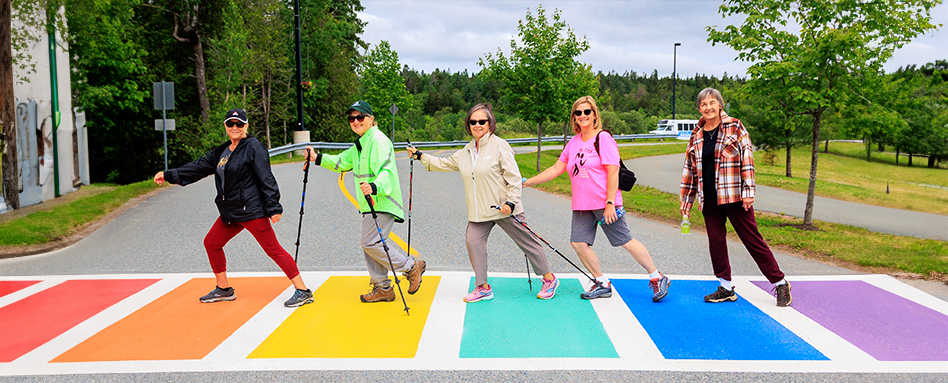 A group of adults walking across a rainbow cross walk 