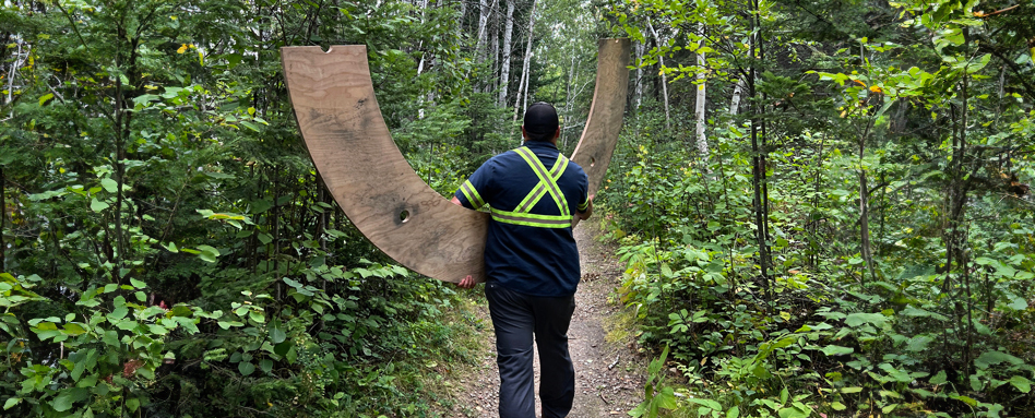 A man carrying a part of the nesting loop wooden material 