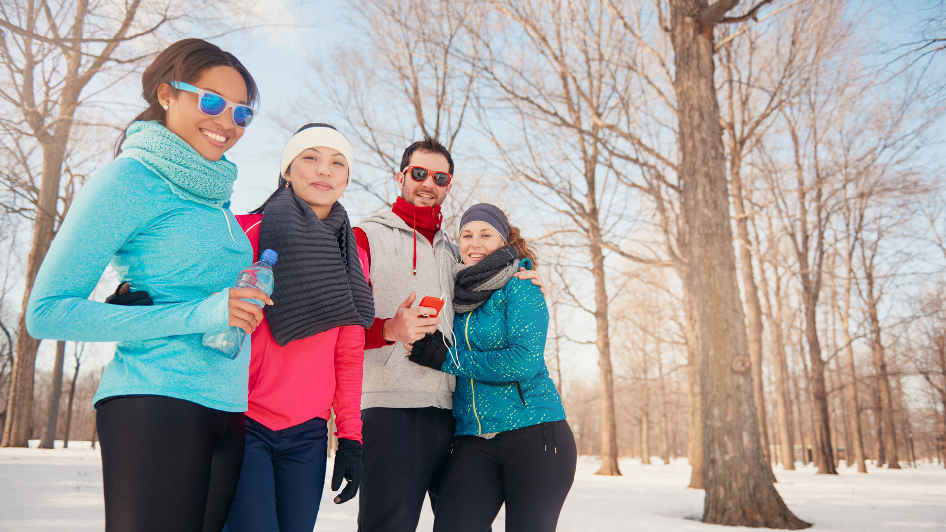 A group of friends smiling outside wearing winter running gear