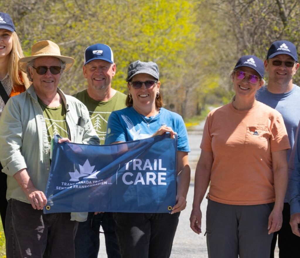 A group of volunteers posing with a Trail Care Banner