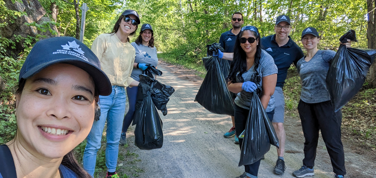 A group of Trans Canada Trail volunteers holding trash bags and cleaning up the trail