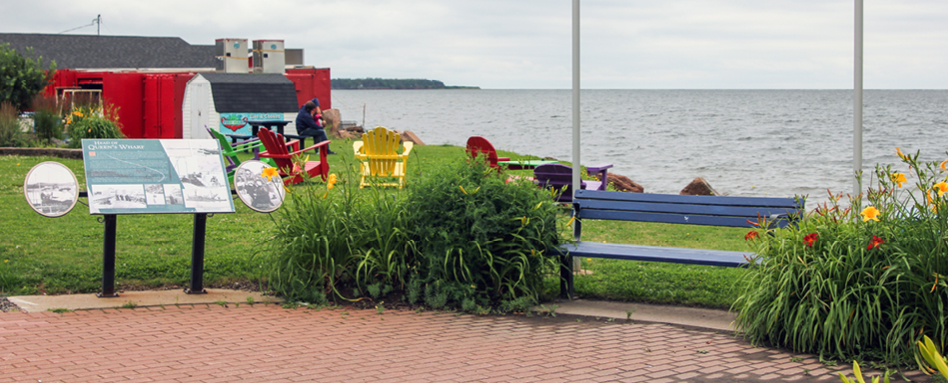 A bench and a sign near the water in Summerside. | Un banc et une pancarte près de l’eau à Summerside.