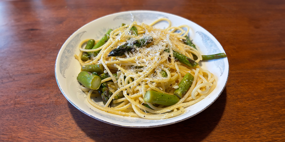 A delicious plate of asparagus pasta topped with parmesan cheese. | Une délicieuse assiette de pâtes aux asperges garnies de parmesan.