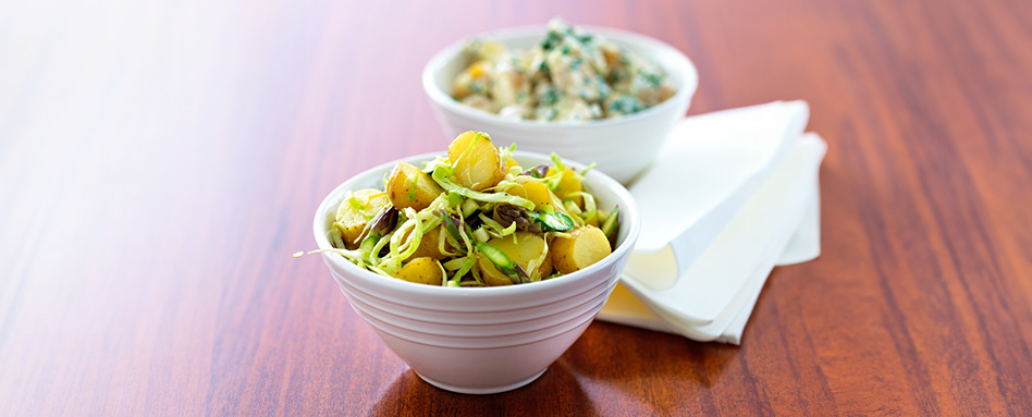 Two bowls of asparagus potato salad on a table. | Deux bols de salade de pommes de terre aux asperges sur une table.