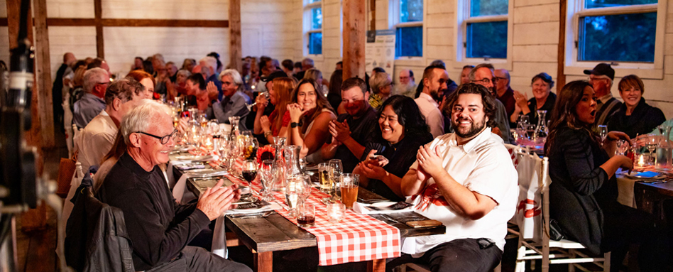 A diverse group of diners enjoying a meal at tables in a bustling restaurant. Un groupe diversifié de convives savourant un repas à des tables dans un restaurant animé.