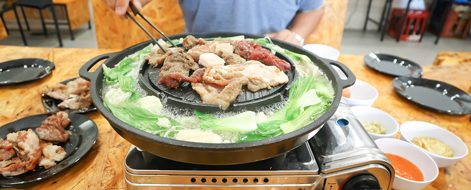 A person preparing a meal in a large pot on a table. répare un repas dans une grande marmite sur une table. Une personne prépare un repas dans une grande marmite sur une table.