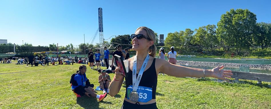 Emily Peotto, a new runner, poses with arms wide open, expressing her excitement post-race. Emily Peotto, une nouvelle coureuse, pose les bras grands ouverts, exprimant son enthousiasme après la course.