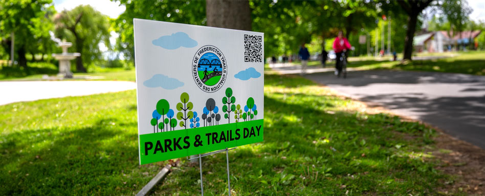 A parks and recreation sign stands prominently in the grass, indicating the area for community activities and leisure. Un panneau de parcs et de loisirs est placé bien en évidence dans l'herbe, indiquant la zone réservée aux activités communautaires et aux loisirs.