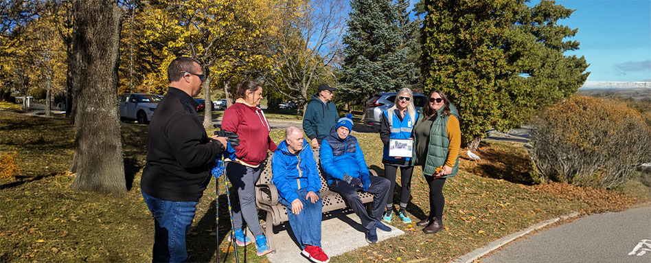 A group of Trail Trekkers sitting together on a park bench, enjoying a sunny day outdoors. Un groupe de membres des « Trail Trekkers » est assis ensemble sur un banc dans un parc, profitant d’une journée ensoleillée à l’extérieur.