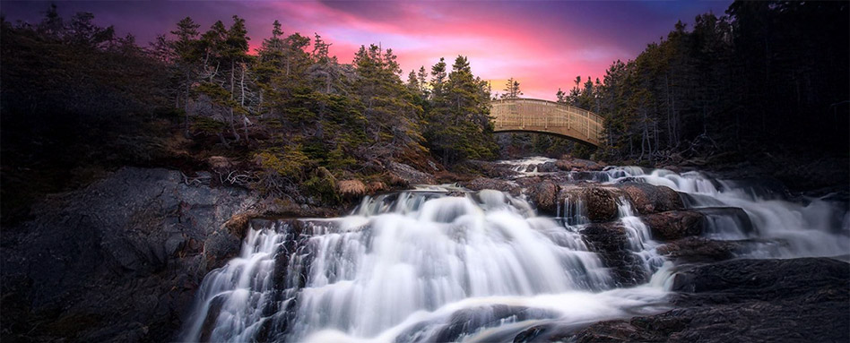 A serene sunset over North Pond Brook, with a waterfall cascading beneath a bridge along the Silver Mine Head Path. Un coucher de soleil serein sur le ruisseau North Pond, avec une cascade tombant sous un pont le long du sentier Silver Mine Head.