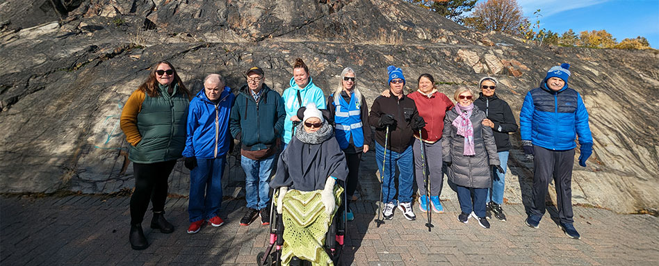 A group of Rainbow Routes team members poses for a photo in front of a scenic rock formation. Un groupe de membres de l’équipe Rainbow Routes pose pour une photo devant une formation rocheuse pittoresque.