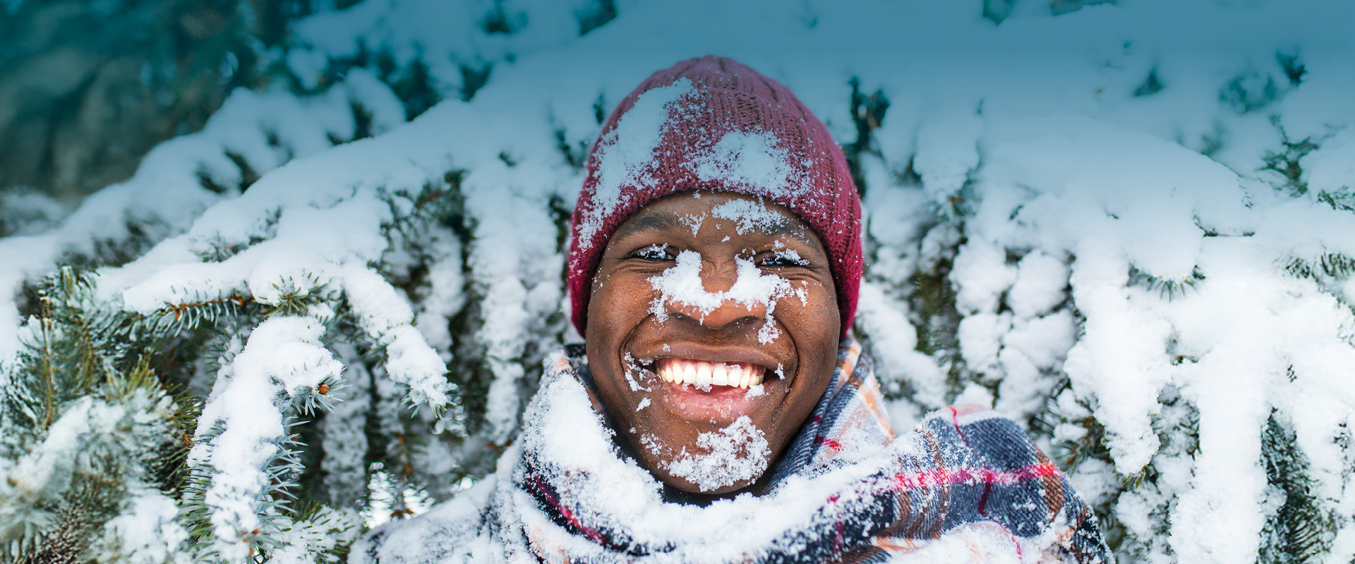 Black man with snow on his face, smiling and enjoying winter on the Trail. Homme noir avec de la neige sur le visage, souriant et profitant de l'hiver sur le Sentier.