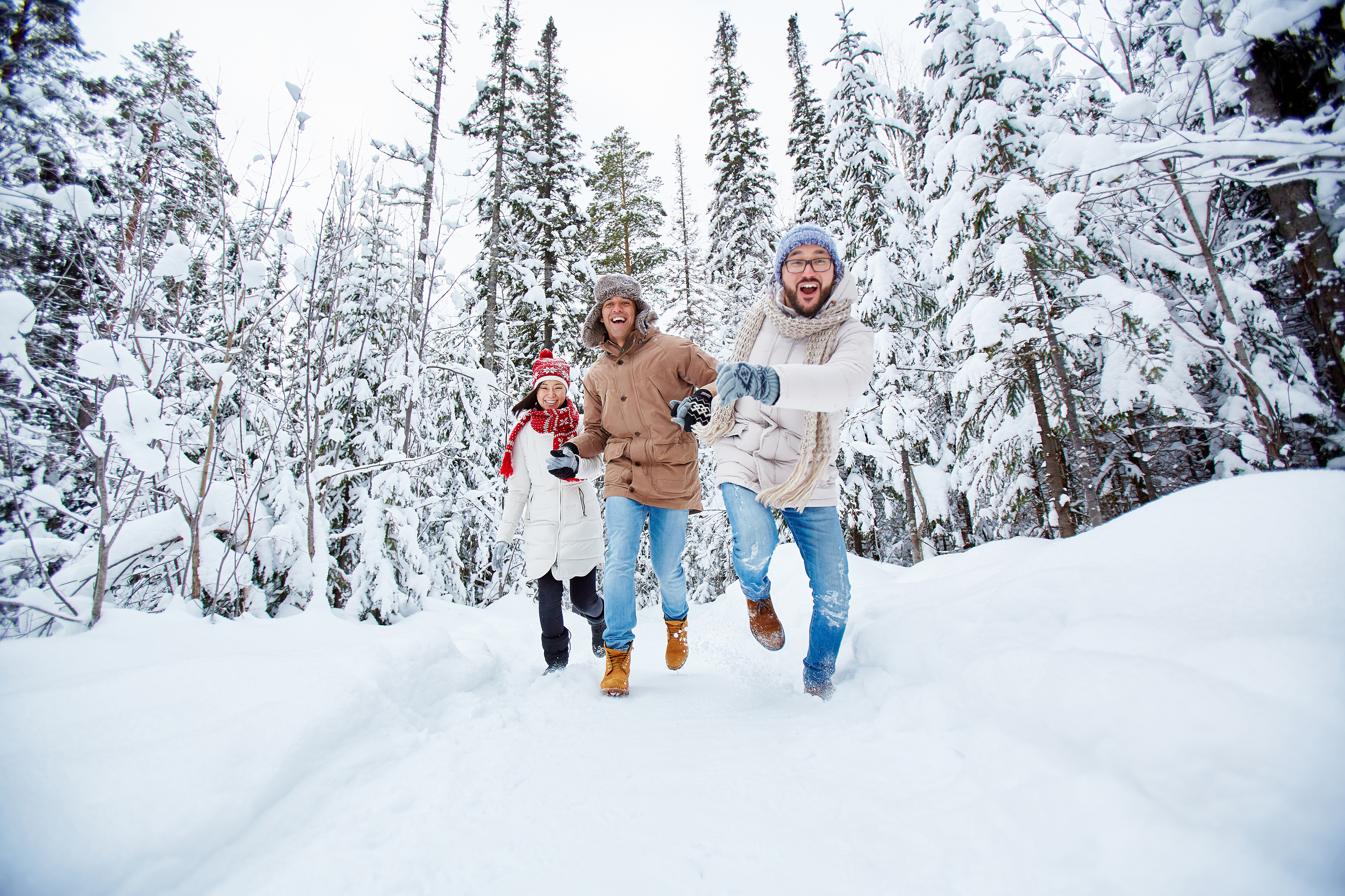 Friends on a hike in the woods, running toward the cameron on a snowy winter day.