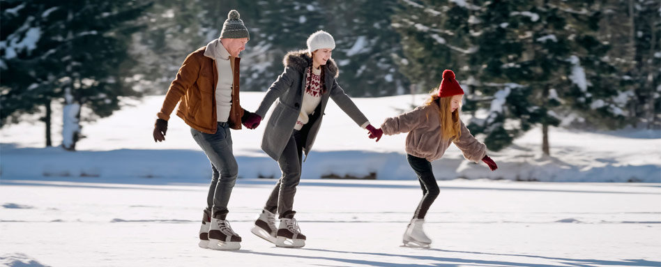 Three people enjoy ice skating on an outdoor ice rink, surrounded by a serene winter landscape. Trois personnes profitent du patinage sur une patinoire extérieure, entourées d’un paysage hivernal paisible.