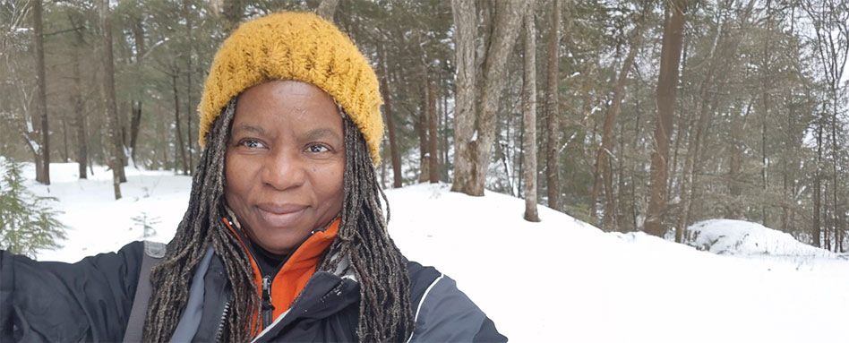 In Sault Ste. Marie, Jacqueline L. Scott poses in the snow, wearing a yellow hat and a black jacket. À Sault Ste. Marie, Jacqueline L. Scott pose dans la neige, portant un bonnet jaune et une veste noire.