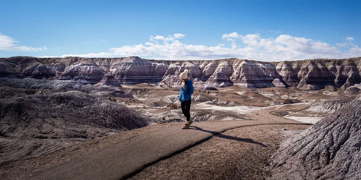 photo of girl standing with blue sky and mountain behind her