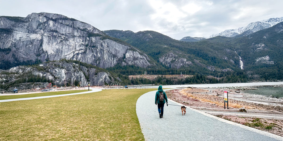 person and dog walking along path with mountainous background