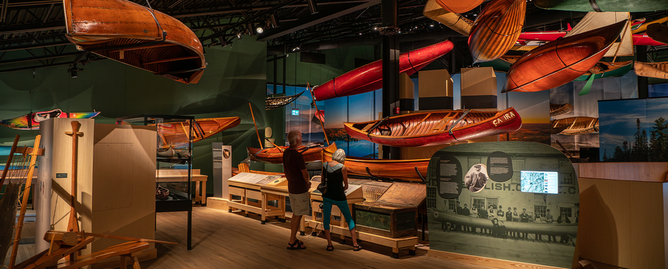 people standing infront of hanging canoes