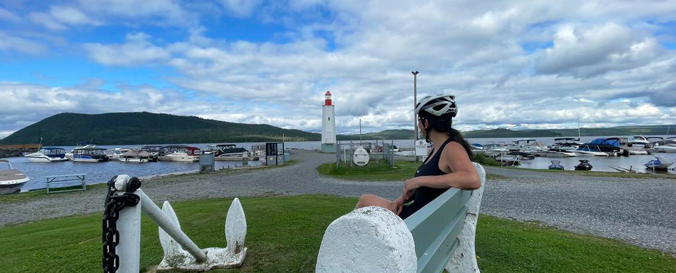 panoramic photo of girl in cycling helmet onlooking a lighthouse on water