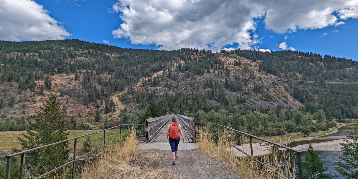 girl walking towards a mountain on a trail