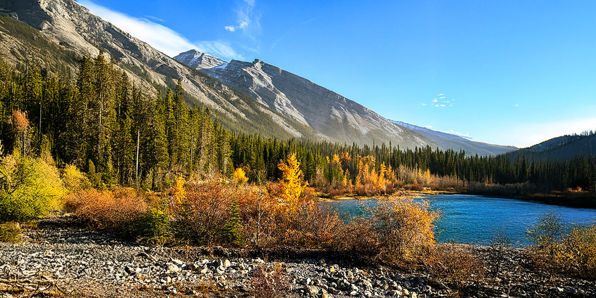 large mountain range behind lake and fall foliage