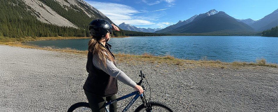 woman on bike looking outwards towards lake and mountains