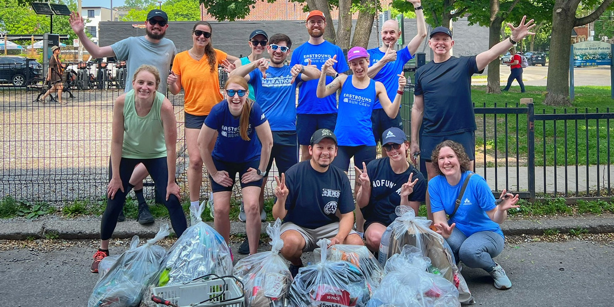 group of people smiling posing with full trash bags