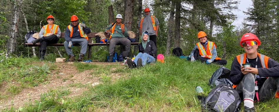 people wearing hard hats and gear sitting on a grass hill
