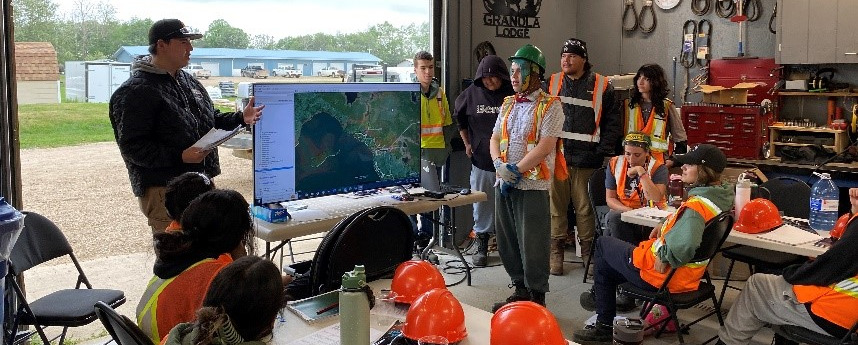 people wearing hardhats and vest looking at tv screen in classroom